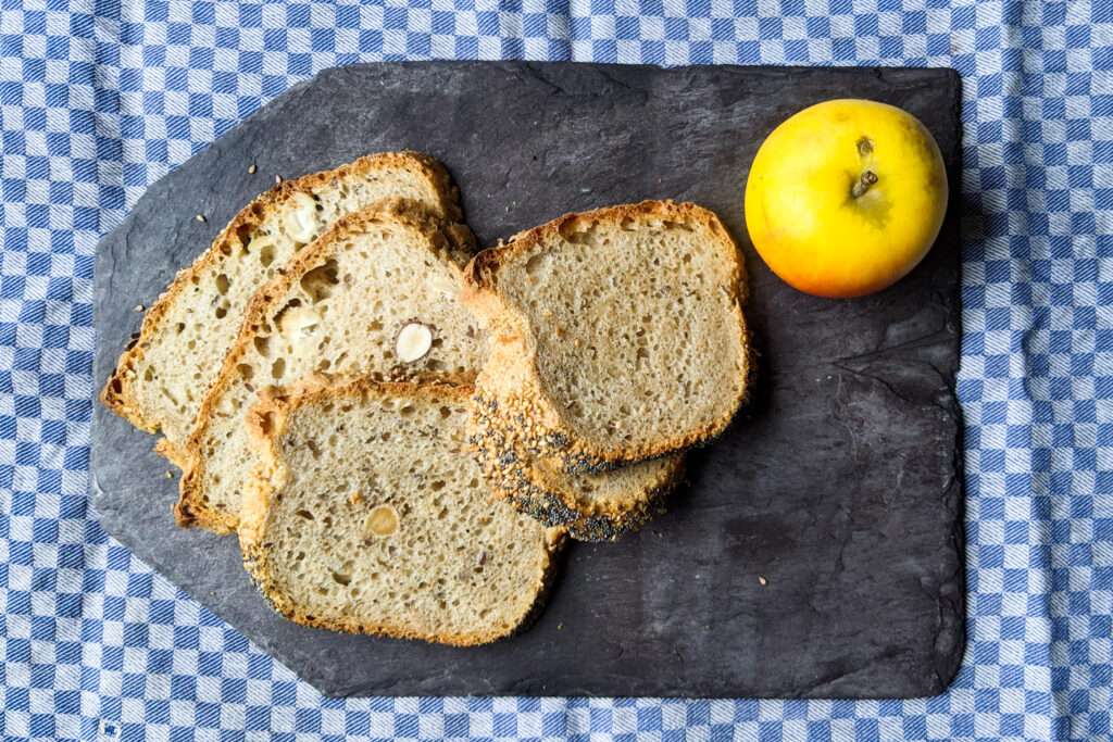 Dinkel-Roggen-Brot, geschnitten, mit Apfel auf blau-kariertem Tuch